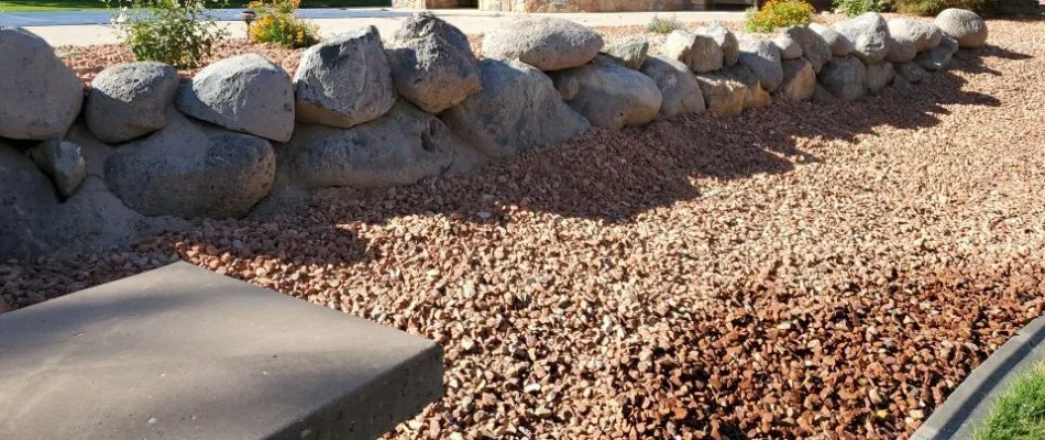 Autumn colored rocks in a landscape bed in Grand Junction, CO, bordered by boulders.