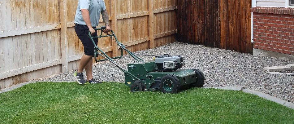 Worker pushing an aerator across a lawn in Grand Junction, CO.