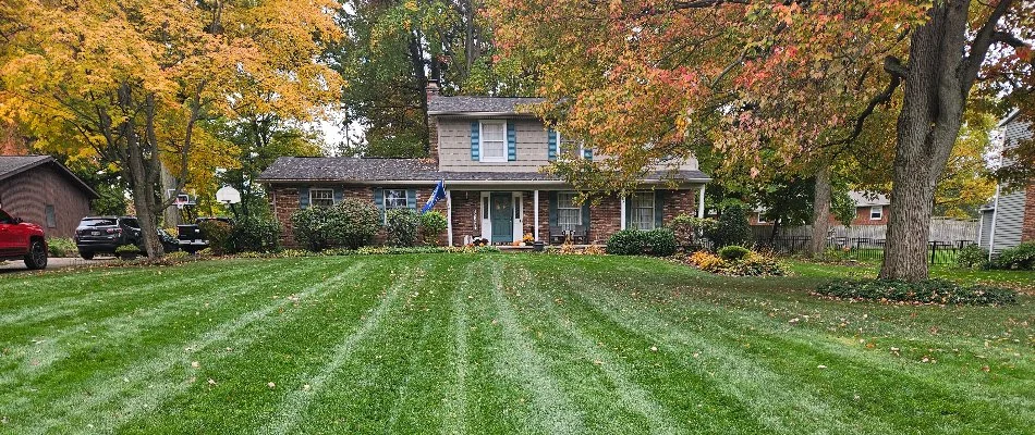 Neatly striped green lawn with autumn foliage in front of a house in Grand Junction, CO.